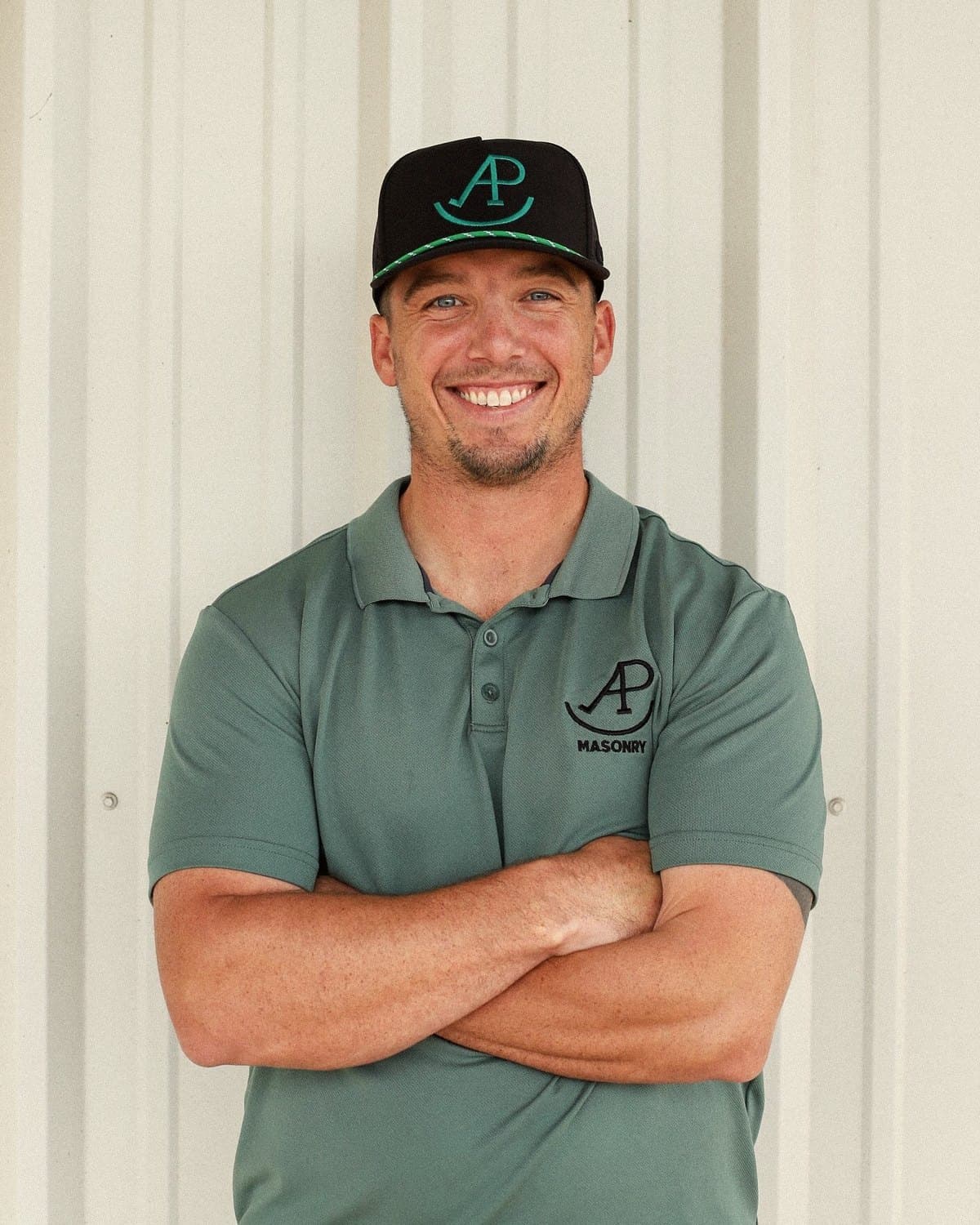 Alex, owner of AP Masonry, in a company polo and cap